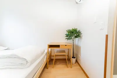 a bedroom with a bed and a desk with a plant at E JOY INN-Higashi Nipoori in Tokyo