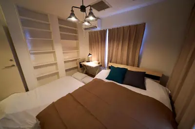 a bedroom with a bed with white sheets and blue pillows at Nakagawa Building - Vacation STAY 17546 in Tokyo