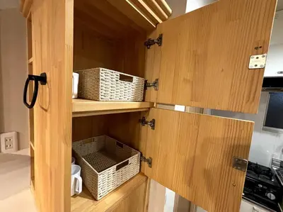 a kitchen with wooden cabinets and baskets on the shelves at \u6771\u6d45\u83492\u4e01\u76eeb201 in Tokyo