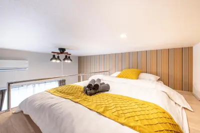a bedroom with a bed with a yellow blanket at Plaza de La Brea in Tokyo