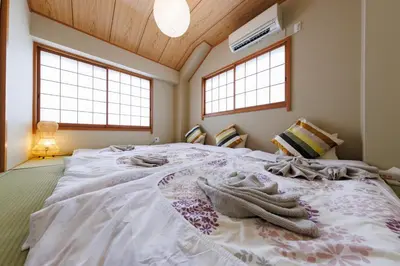 a bedroom with a large white bed with two windows at Bliss KAMEARI in Tokyo