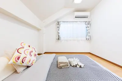 a bedroom with a bed with two towels and a window at Bliss KAMEARI in Tokyo