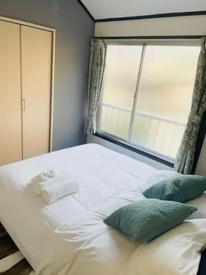 a white bed with a window and towels on it at RED House｜12 minutes from the station｜Quiet area｜Direct access to Shinjuku & Akihabara in Tokyo