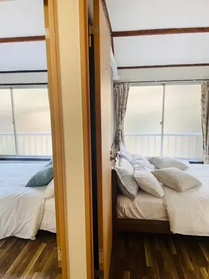 a bedroom with two beds and two windows at RED House｜12 minutes from the station｜Quiet area｜Direct access to Shinjuku & Akihabara in Tokyo