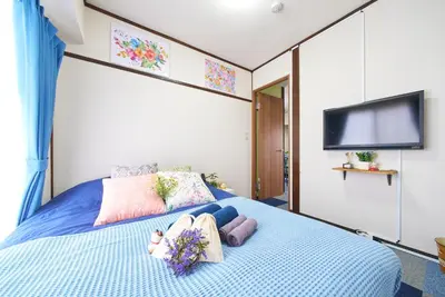a bedroom with a blue bed with a flat screen tv at Belmont 301 3min to Station Easy Access Ueno Asakusa Skytree Sleeps 5 in Tokyo