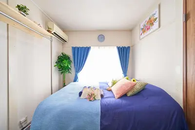 a bedroom with a blue bed with pillows and a window at Belmont 302 3min to Station Easy Access Ueno Asakusa Skytree Sleeps 5 in Tokyo