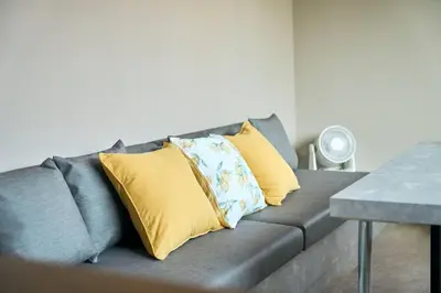 a gray couch with yellow pillows in a living room at \u6771\u6d45\u83492\u4e01\u76ee\u6238\u5efa in Tokyo