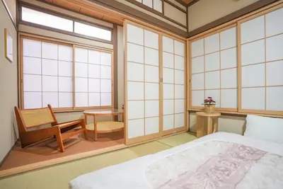 a bedroom with a bed and a chair and windows at Asakusa 5 Chome KazeNoItsu Home in Tokyo