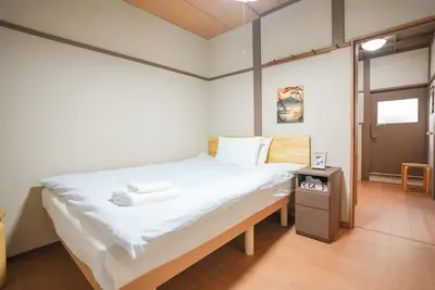 a bedroom with a large bed with white sheets at Asakusa 5 Chome KazeNoItsu Home in Tokyo