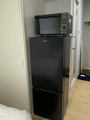 a microwave sitting on top of a black refrigerator at Shinjuku 2 stops, 3 people,station walk for 4 mins in Tokyo