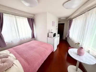 a bedroom with a pink bed and a table at Ikebukuro-Kanamecho Studio - 2 Seconds from Kanamecho Station - Comfortable & Central 3F in Tokyo