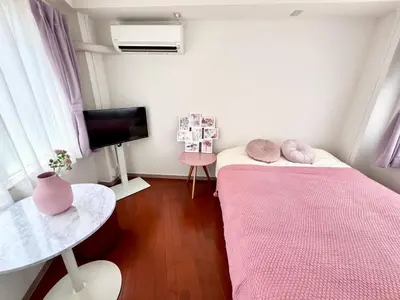 a small room with a pink bed and a table at Ikebukuro-Kanamecho Studio - 2 Seconds from Kanamecho Station - Comfortable & Central 3F in Tokyo