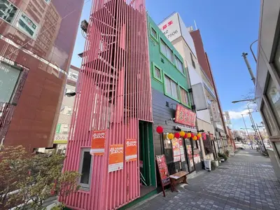 a pink building on a street in a city at Ikebukuro-Kanamecho Studio - 2 Seconds from Kanamecho Station - Comfortable & Central 3F in Tokyo