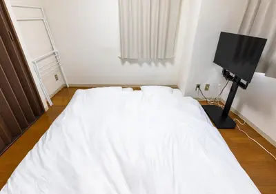 a white bed in a room with a television at Benir Maison Izumi in Tokyo