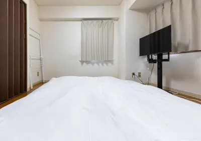 a bedroom with a white bed and a flat screen tv at Benir Maison Izumi in Tokyo