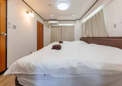 a bedroom with a large white bed with a window at Benir Maison Izumi in Tokyo