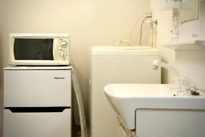 a microwave sitting on top of a refrigerator next to a sink at Green & Orange House - Economic APT in Tokyo Tranquil Block, with Direct Access to Ginza & Akihabara in Tokyo