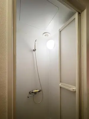 a shower in a bathroom with a light on the wall at Green & Orange House - Economic APT in Tokyo Tranquil Block, with Direct Access to Ginza & Akihabara in Tokyo