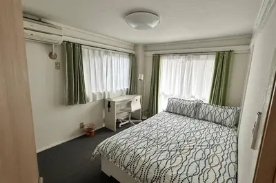a bedroom with a bed and a desk and windows at Warmhome-hirai2F in Tokyo