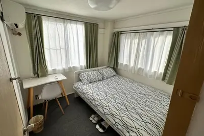 a bedroom with a bed and a desk and two windows at Warmhome-hirai3F in Tokyo