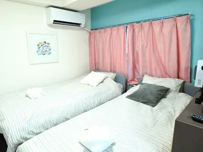 two beds in a small room with pink curtains at \u5927\u68ee\u30d3\u30c3\u30b0\u30d5\u30a9\u30ec\u30b9\u30c8-Oomori Big Forest- \u7fbd\u7530\u7a7a\u6e2f \u54c1\u5ddd \u6771\u4eac\u307e\u3067\u30a2\u30af\u30bb\u30b9\u826f\u597d \u7121\u6599Wi-Fi in Tokyo