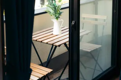 a table and a vase on a balcony with a plant at Garfield home Shinjuku in Tokyo