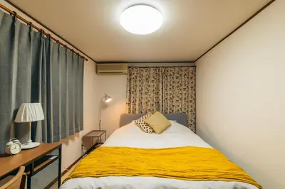 a bedroom with a bed with a yellow blanket at Garfield home Shinjuku in Tokyo