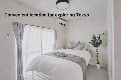 a white bedroom with a bed and a window at Cosmo in Tokyo
