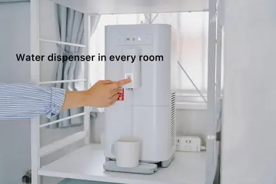 a person is using a water dispenser in a room at Cosmo in Tokyo