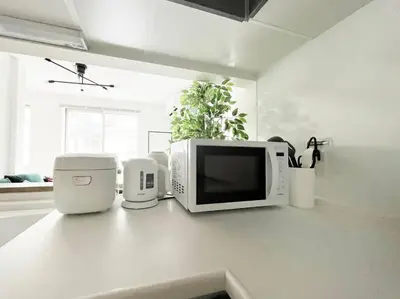 a kitchen counter with a microwave and other appliances on it at Tnw\u5317\u65b0\u5bbf4\u4e01\u76ee in Tokyo