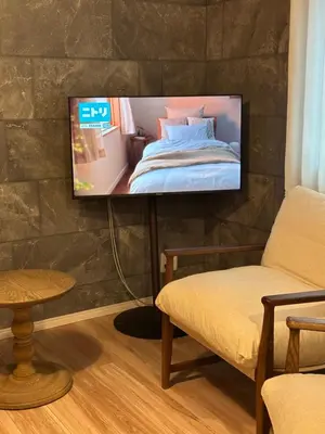 a flat screen tv hanging on a wall with a bed at Wasabi Box House - Ikebukuro Area in Tokyo
