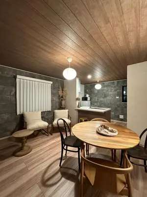 a living room with a wooden ceiling and a table and chairs at Wasabi Box House - Ikebukuro Area in Tokyo