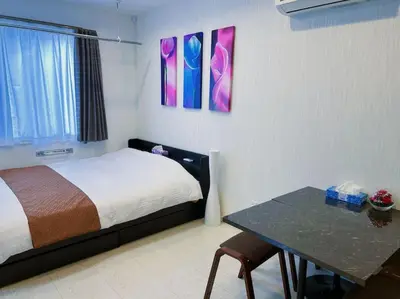 a room with a bed and a table and paintings at yuga hotel tokiwadai in Tokyo