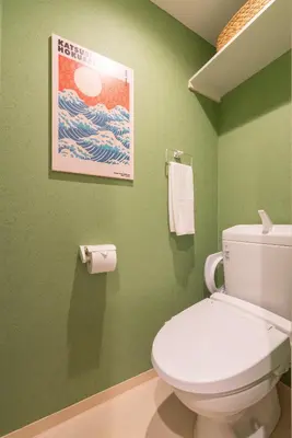a bathroom with a white toilet in a green wall at Karabiner House Hikihune in Tokyo