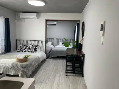 a bedroom with two beds and a desk and a sink at COMMA HOUSE Otsuka 102 in Tokyo
