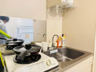 a kitchen with a sink and a stove with a pan on it at shinjukuFleur in Tokyo