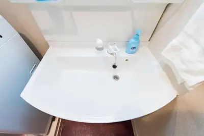 a white bathroom sink with a blue bottle on it at unito \u9053\u7384\u5742\u90b8\u5b85 in Tokyo