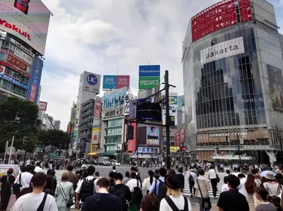 a crowd of people crossing a street in a city at unito \u9053\u7384\u5742\u90b8\u5b85 in Tokyo