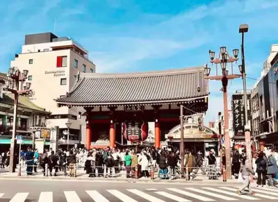 a group of people crossing a street in front of a building at \u30b5\u30af\u30e9 in Tokyo