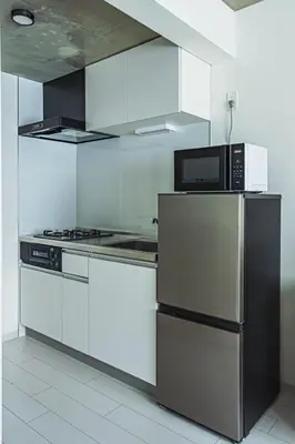 a kitchen with white cabinets and a microwave and a refrigerator at AT Asakusa in Tokyo