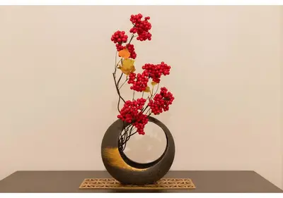 a black vase with red flowers in it on a table at Lido Alba in Tokyo