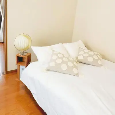 a white bed with pillows and a lamp on a table at Oshiage Sta U-Court Kinshicho in Tokyo