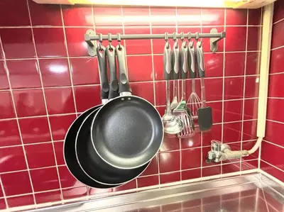 a pan hanging on a red tiled wall with utensils at \u6c60\u888b\u99c5\u307e\u3067\u96fb\u8eca\u30677\u5206 4LDK98m2 in Tokyo
