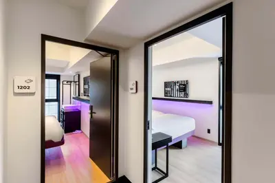 a room with a bed and a door with a mirror at YOTEL Tokyo Ginza in Tokyo