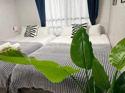 a bedroom with two beds and a plant at COMMA HOUSE Otsuka 201 in Tokyo