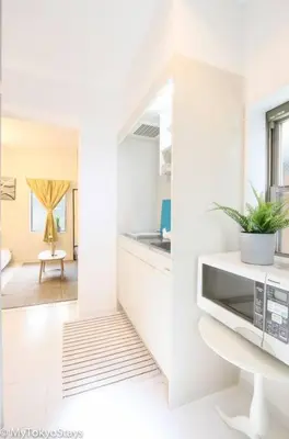 a white kitchen with a plant on a counter at NEW! Downtown Shibuya Prime Unit, Perfect location in Tokyo
