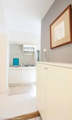 a kitchen with white cabinets and a picture on the wall at NEW! Downtown Shibuya Prime Unit, Perfect location in Tokyo