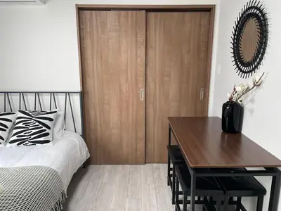 a bedroom with a bed and a wooden closet at COMMA HOUSE Otsuka 202 in Tokyo