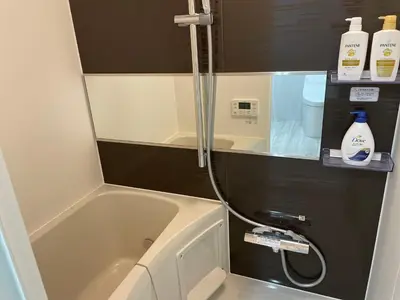 a bathroom with a tub and a shower with a hose at COMMA HOUSE Otsuka 203 in Tokyo