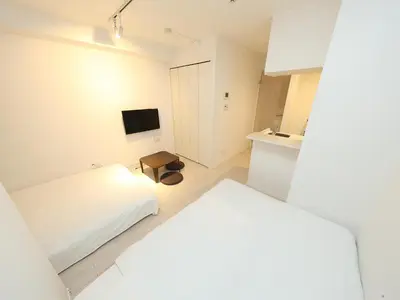a small white bedroom with a bed and a tv at - KOMA Hotel- \u6d45\u8349\u99c5\u5f92\u6b696\u5206 \u7bc9\u6d45\u3067Wi-Fi\u4ed8\u304d \u5bb6\u5177\u5bb6\u96fb\u5145\u5b9f in Tokyo